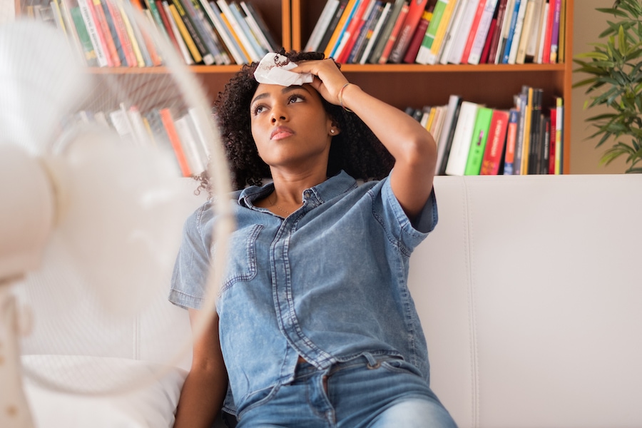 Black woman sweating and trying to refresh at home.