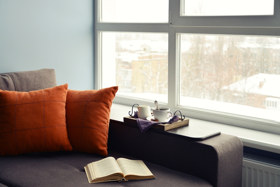 Cup of coffee on vintage tray on sofa with open book.