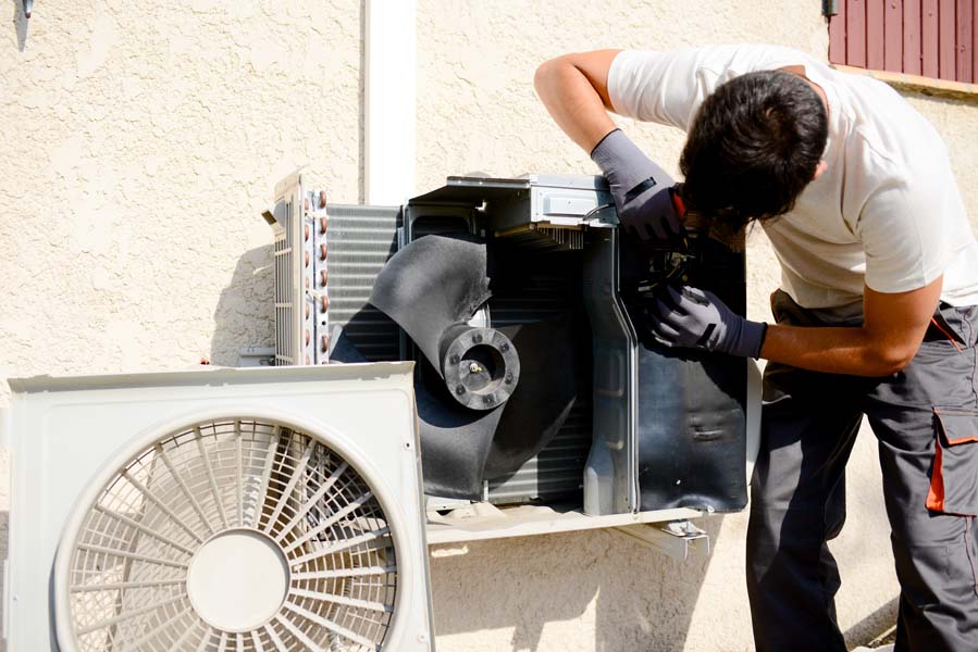 young man electrician installer working on split system air conditioner unit at a client's home in Ontario, OR