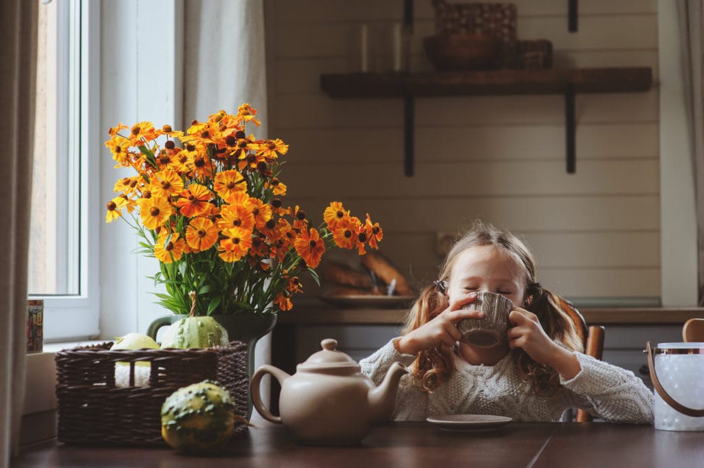 child girl having breakfast at home in summer morning