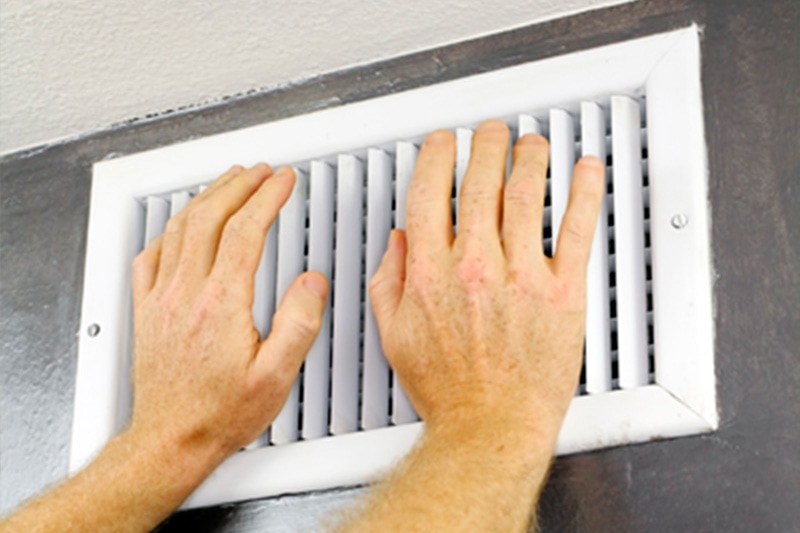 person putting their hands over an air condition vent