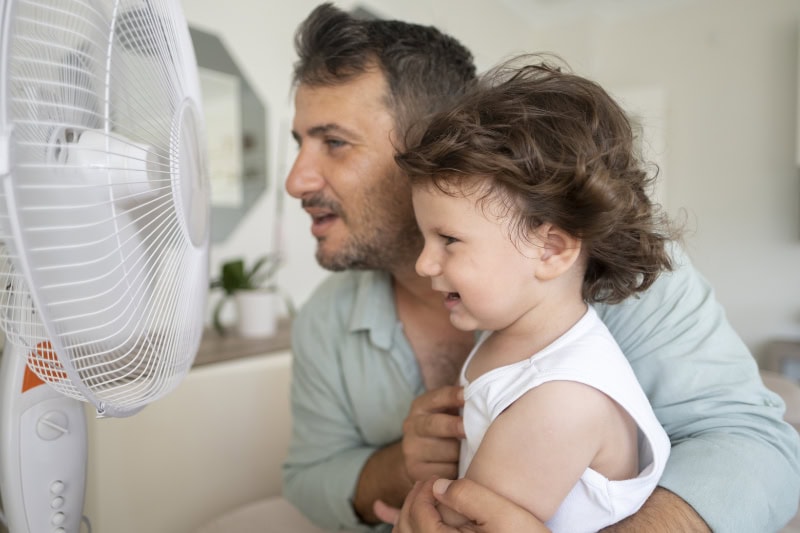 Dad and daughter in front of fan.