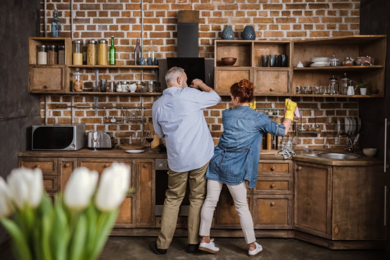 How a Whole-House Humidifier Keeps You Healthy. Back view of mature couple having fun while washing dishes.
