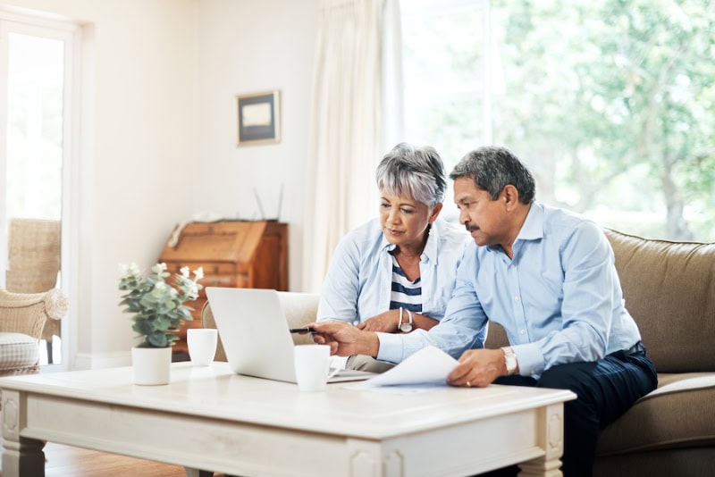 What Do Air Purifiers and Air Filters Do? Photo of senior couple sitting in their living room on a laptop.
