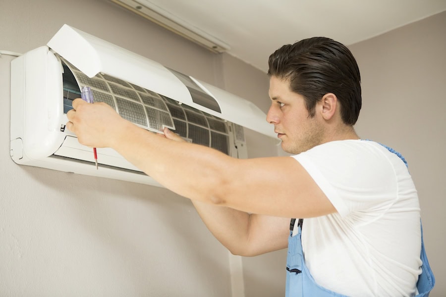 Young technician repairing air conditioner at home.